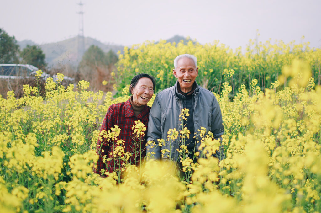 image of elderly couple laughing in a flower field